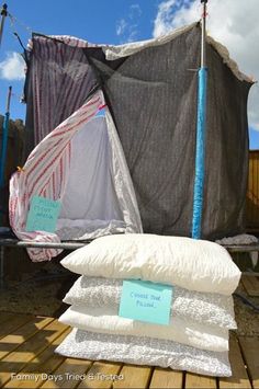 there are many pillows and sheets on the ground next to a tent with a tarp over it