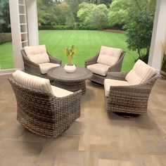 wicker patio furniture set in front of a large open area with grass and trees