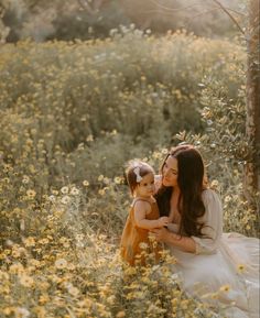 a woman holding a small child in a field of flowers