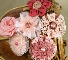 several pieces of fabric with flowers and pearls on them sitting on a wooden chair in front of a wall