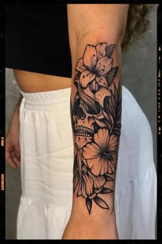 a woman's arm with a skull and flowers on it