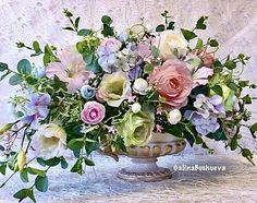 a vase filled with lots of flowers on top of a white cloth covered tablecloth