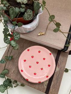 a pink plate sitting on top of a table next to a potted plant