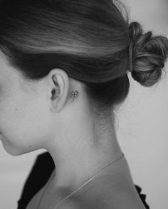 a woman with a small tattoo on her left side of her neck and behind her ear