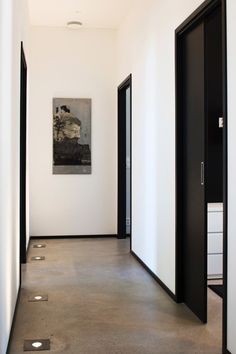 an empty hallway with black doors and white walls