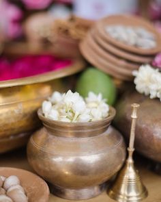 there are many different types of items on the table with white flowers in pots and bowls