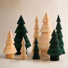 several small wooden trees are lined up against a white background and one is made out of folded paper