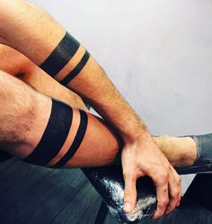 a man sitting on top of a wooden floor with his legs wrapped in black tape