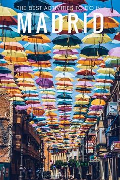 colorful umbrellas are hanging from the ceiling above a street in madrid, spain with text overlay that reads the best activities to do in madrid