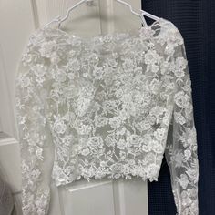 a white lace top hanging on a door