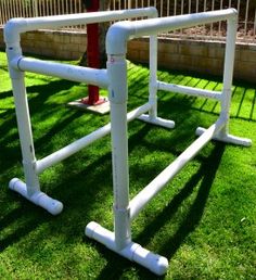 the white pipes are attached to the red fire hydrant on the grass field in front of the fence