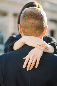 a man and woman hug each other in front of a building