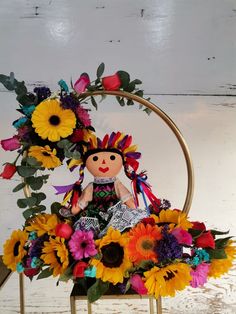 a small doll sitting on top of a chair with sunflowers and flowers around it