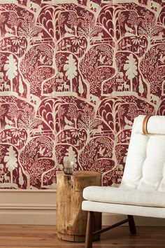 a white chair sitting in front of a wall with red and white designs on it