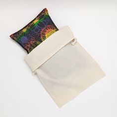 two small bags are sitting next to each other on a white surface, one is folded and the other has a multicolored design