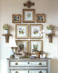 a white dresser topped with lots of pictures and vases filled with flowers on top of it