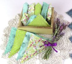 a box filled with green and blue napkins on top of a lace doily