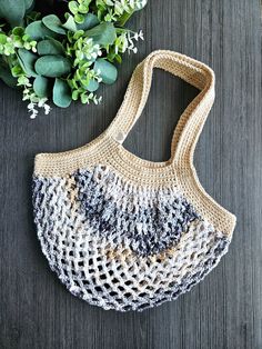 a crocheted bag sitting next to a green plant