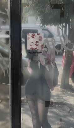 the reflection of a woman walking past a store window with her back to the camera