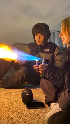 two people are sitting on the ground and one is holding a light saber