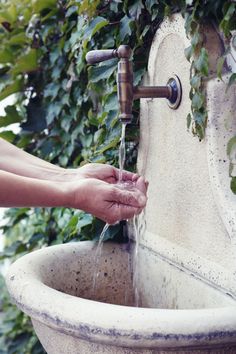 a person is washing their hands under a water fountain