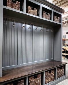 a wooden bench with baskets on it in front of a wall filled with shelves and bins