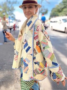 a woman walking down the street with a hat on and holding a cell phone in her hand