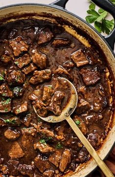 a pot filled with beef stew and a wooden spoon