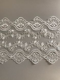 an embroidered lace with flowers and leaves on the side, in white color is shown