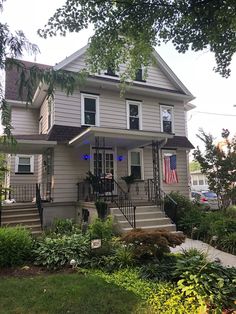 a two story house with an american flag on the porch