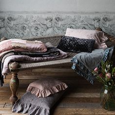 a bed sitting on top of a wooden floor next to a vase filled with flowers