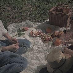 two people sitting on a blanket with food and drinks