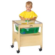 a young boy sitting in a wooden chair with a green container on it's side