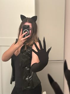 a woman taking a selfie in front of a mirror with her cat costume on