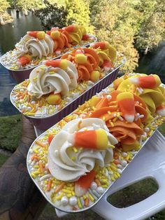 three trays filled with cupcakes on top of a table next to water