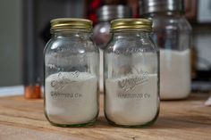 two glass jars filled with sand sitting on top of a wooden table