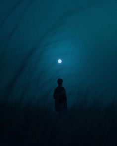 a man standing in the middle of a foggy field with a full moon behind him