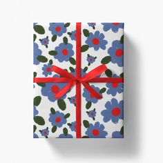 a gift wrapped in blue and red flowers with a red ribbon