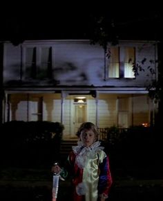 a woman dressed as santa clause holding a bottle in front of a house at night