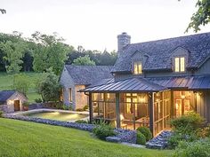 the house is surrounded by lush green grass and stone walls, along with an outdoor swimming pool