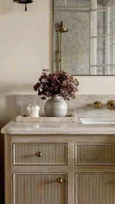 a vase with flowers on top of a bathroom vanity