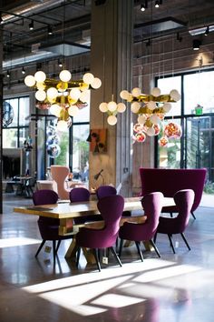 a dining room table with purple chairs and chandelier hanging from it's ceiling