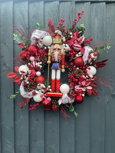 a christmas wreath with a nutcracker and decorations hanging on the side of a fence