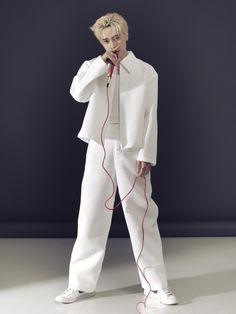 a male in a white suit and headphones is standing with his hands on his chin