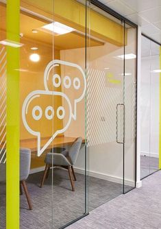 an office meeting room with glass walls and bright yellow accenting the wall behind it