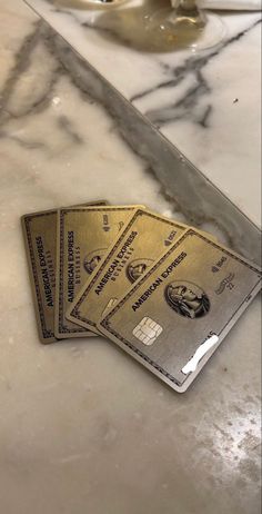 three credit cards sitting on top of a counter next to a knife and some cups