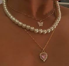 a woman wearing pearls and a necklace with a heart shaped pendant hanging from it's side