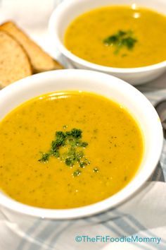 two bowls of soup with bread on the side