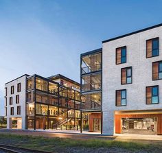 an apartment building with many windows on the side of it and train tracks in front