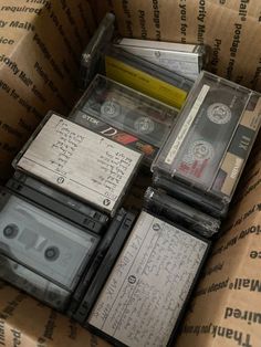 several cassettes are stacked on top of each other in a cardboard box with writing on them